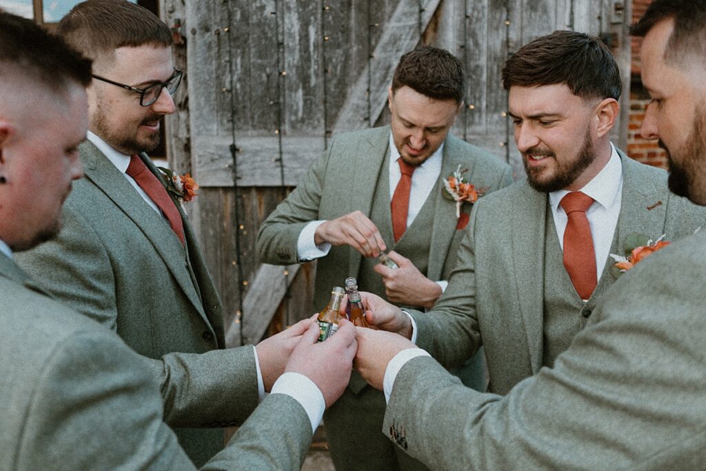 a group groomsmen saying cheers to each other with miniature spirit drinks at Ufton Court in Aldermaston