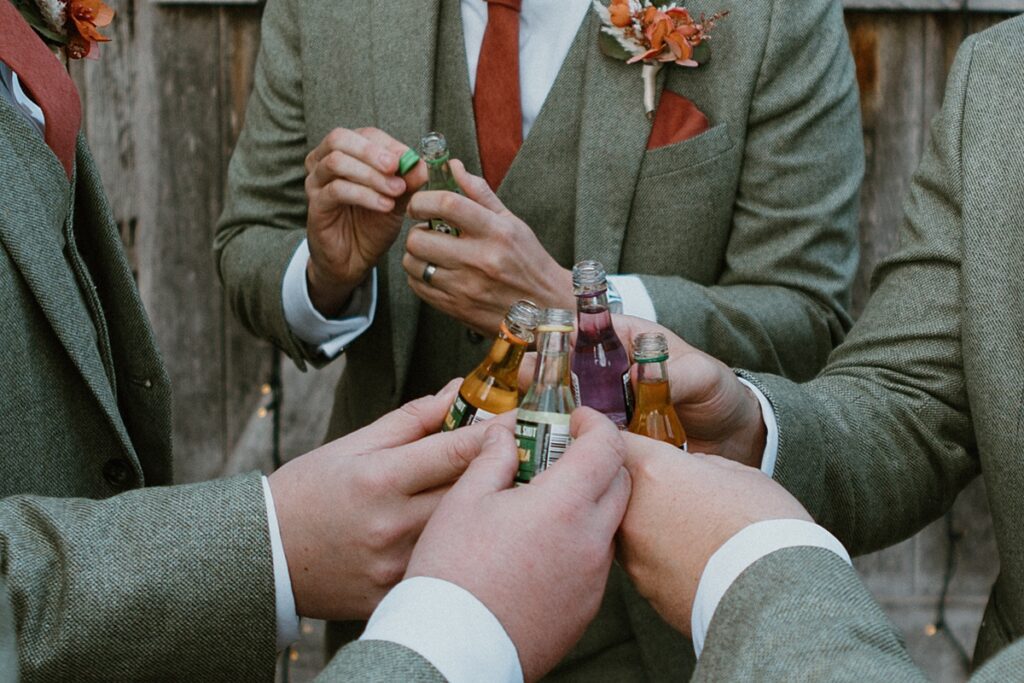 a close up of a group groomsmen saying cheers to each other with miniature spirit drinks at Ufton Court in Aldermaston