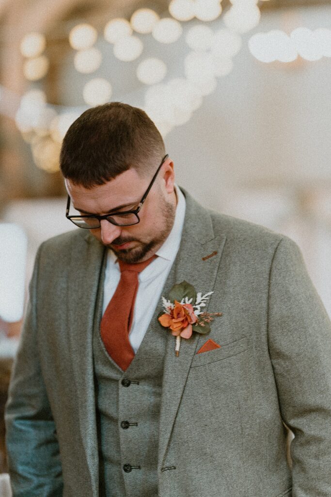 a groom looking nervous and down at his feet waiting for his bride to arrive at Ufton Court