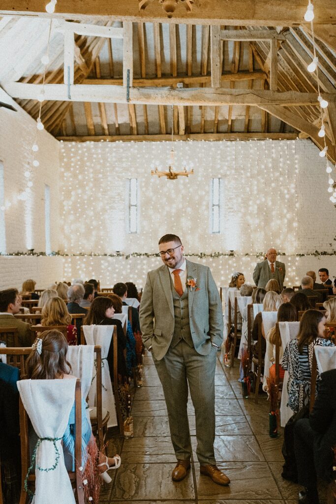 a groom stood in the middle of the ceremony aisle waiting for his bride to arrive for his wedding