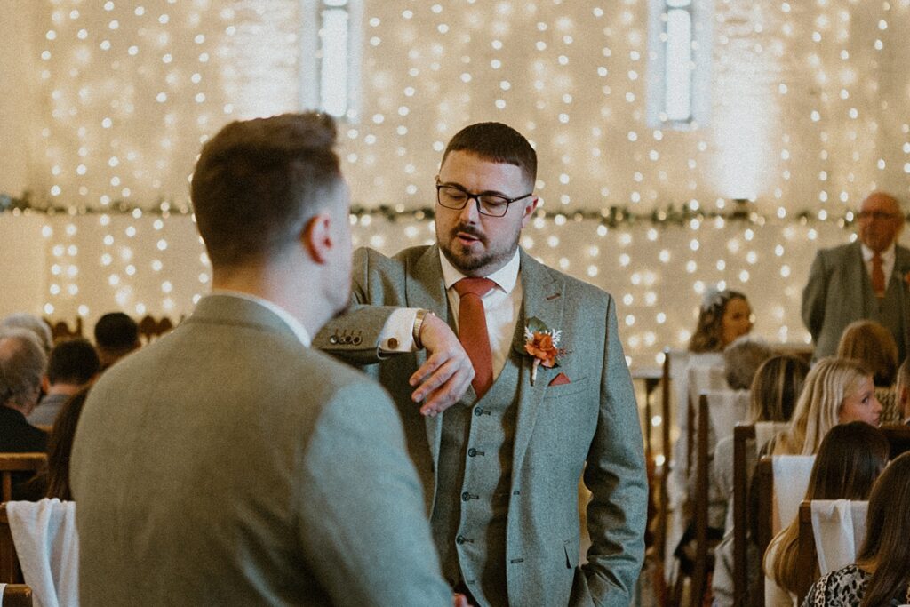 a groom checking his watch as he waits for his bride to be arrive ready for their wedding