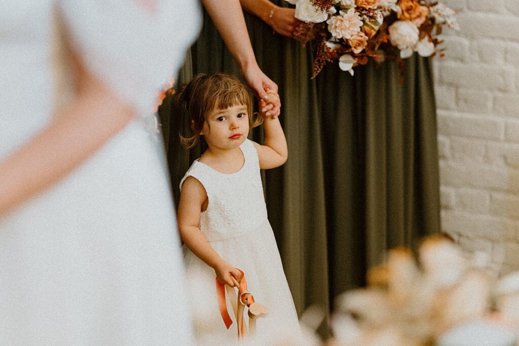 a flower girl holding her mums hand during a wedding ceremony at Ufton Court