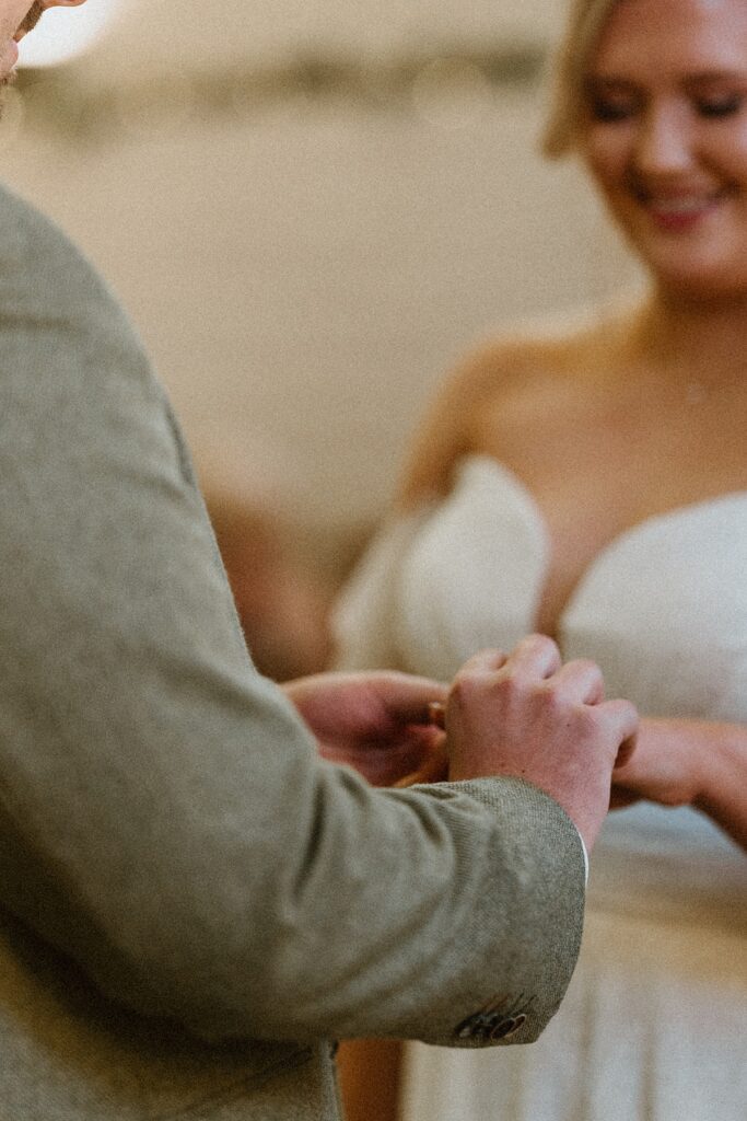 a close up of a groom putting a ring on his wifes finger