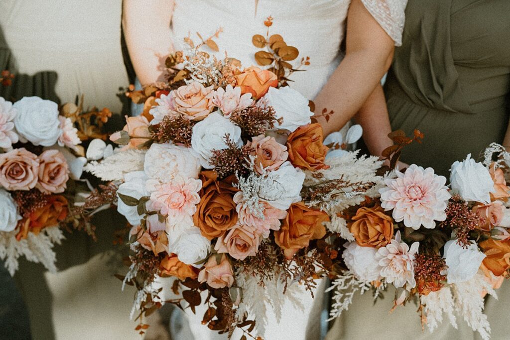 a close up of a brides bouquet with brown, orange, white and cream flowers