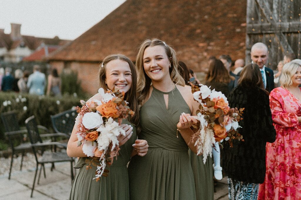 2 bridesmaids hugging in to each other and smiling at the camera for a newbury ufton court wedding photographer