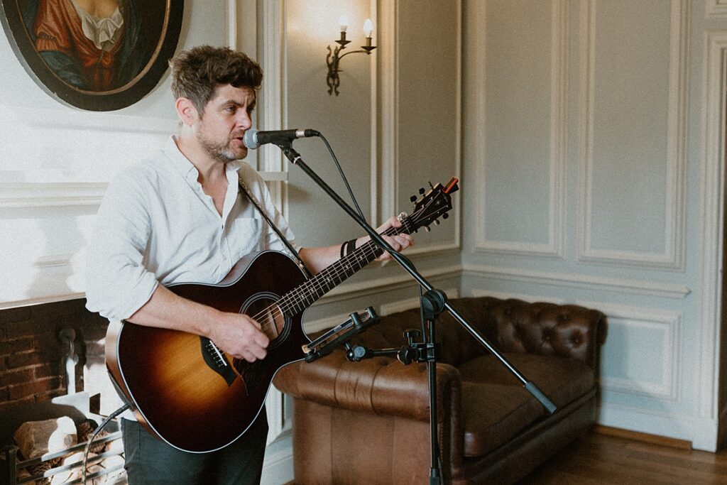 a male singer performing at a wedding reception with a guitar in his hands