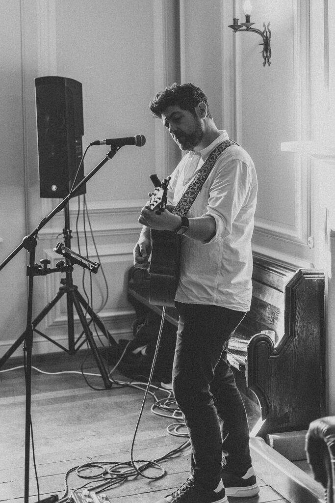 a male singer performing at a wedding reception with a guitar in his hands