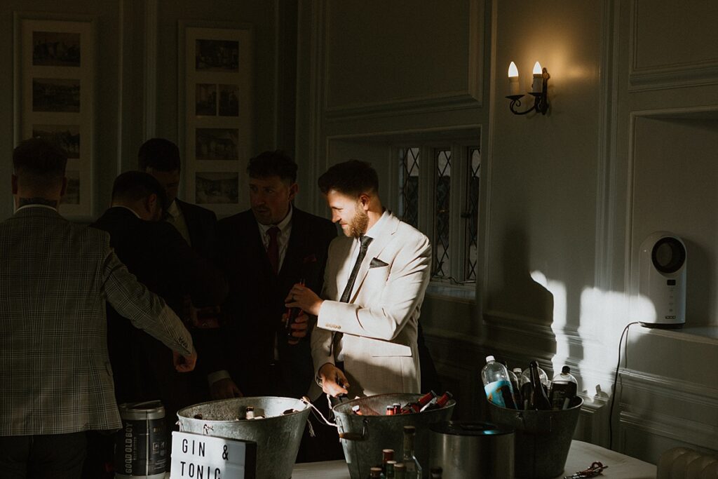 a wedding guest lit by the sun as he helps himself to a beer at a wedding reception