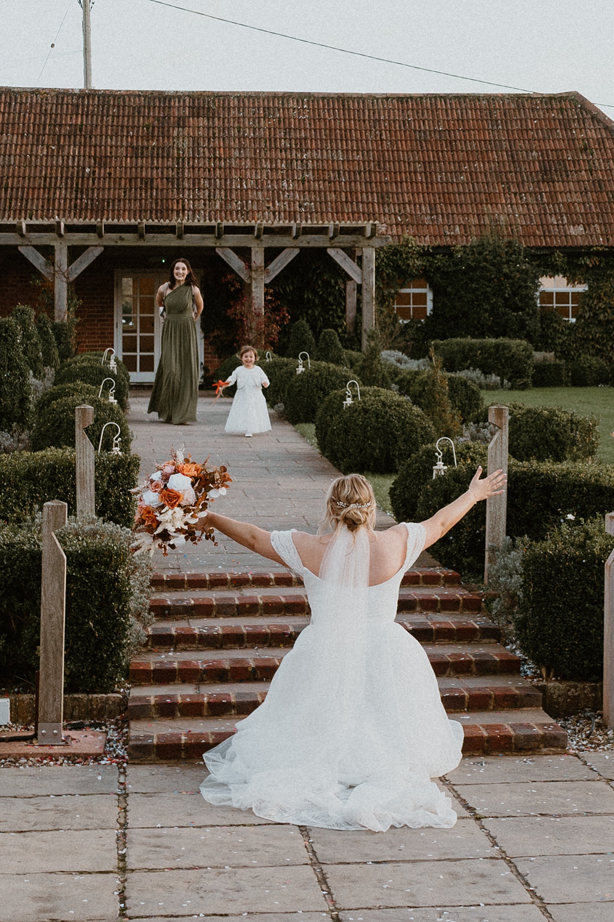 a bride crouching down day and waiting for a flower girl to run into her arms at Ufton Court Barn