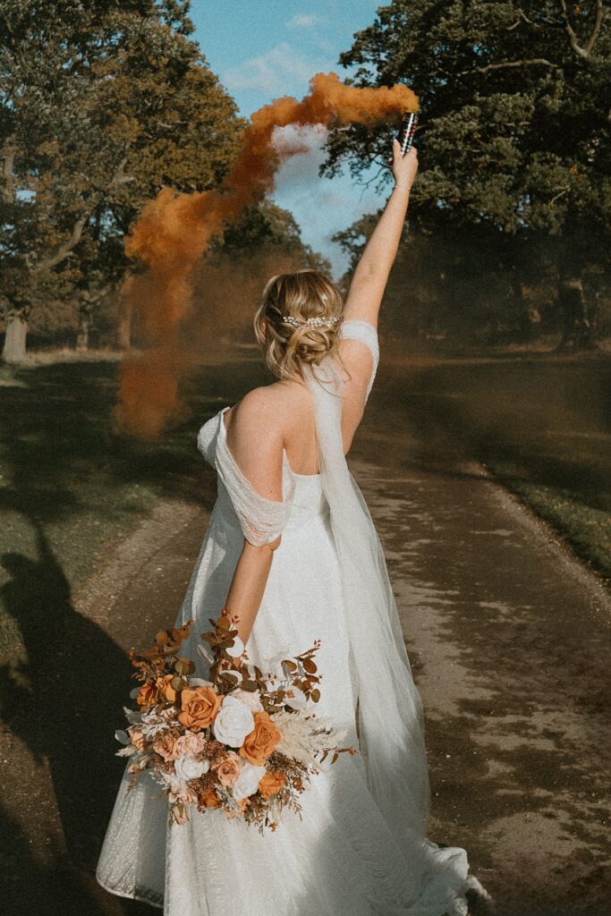 a bride waving an orange smoke grenade during her wedding day