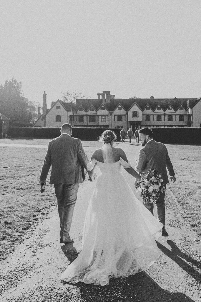 a black and white image of a wedding party walking away from luxury wedding photographer