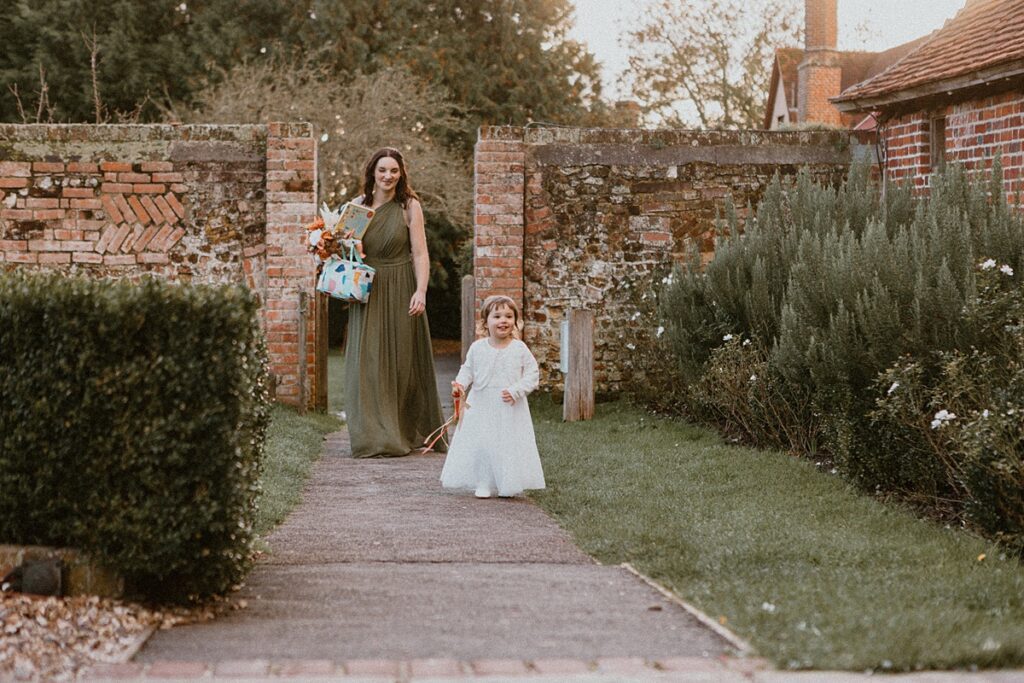 a bridesmaid and a flower girl walking down a path way at Ufton Court