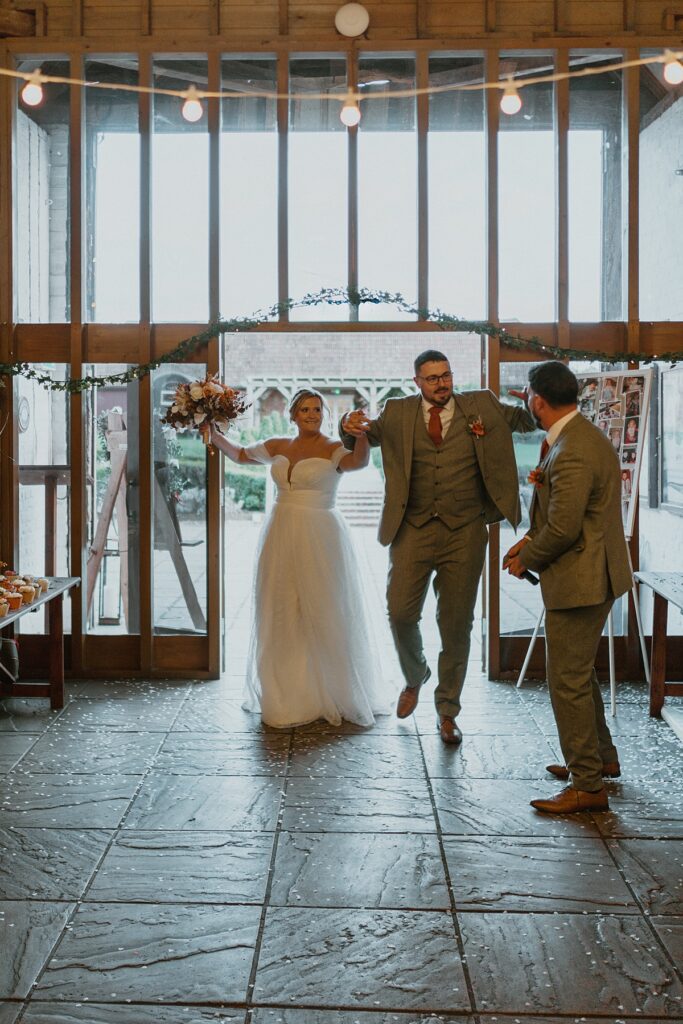 a bride and groom cheering and celebrating as they walk into their wedding breakfast room at Ufton Court