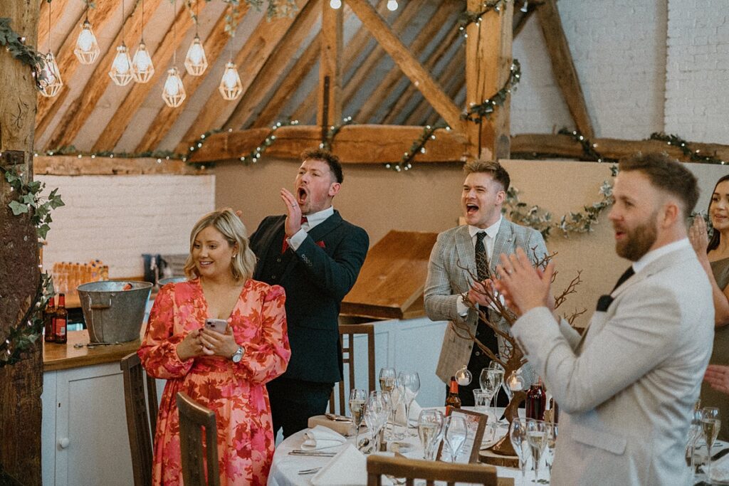 guests cheer on as the bride and groom walk into the wedding breakfast room at Ufton Court