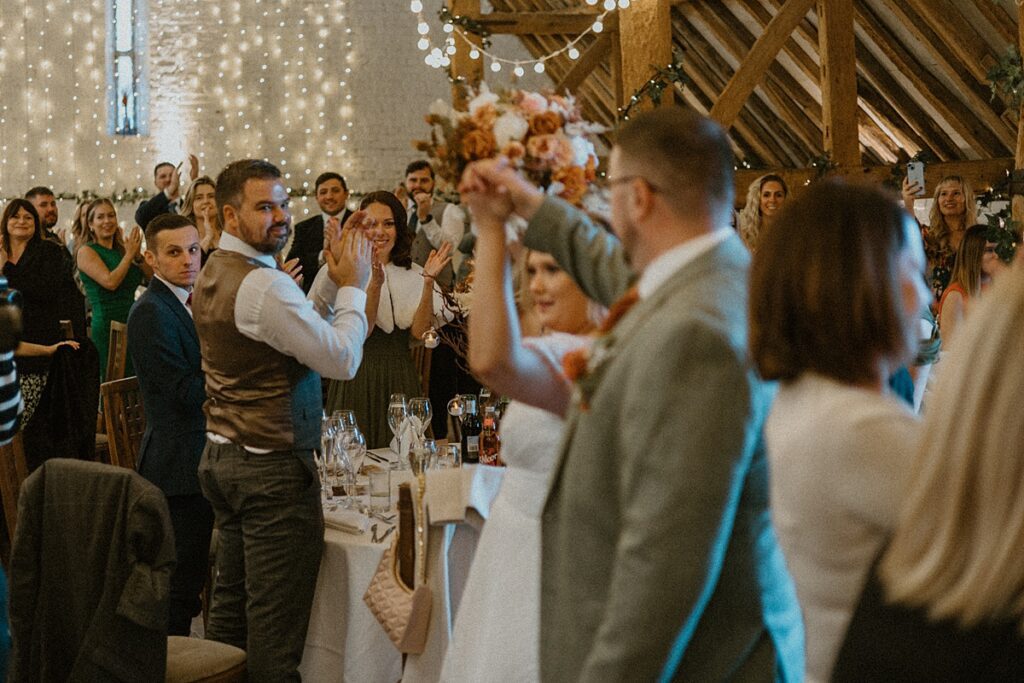 guests cheer on as the bride and groom walk into the wedding breakfast room at Ufton Court