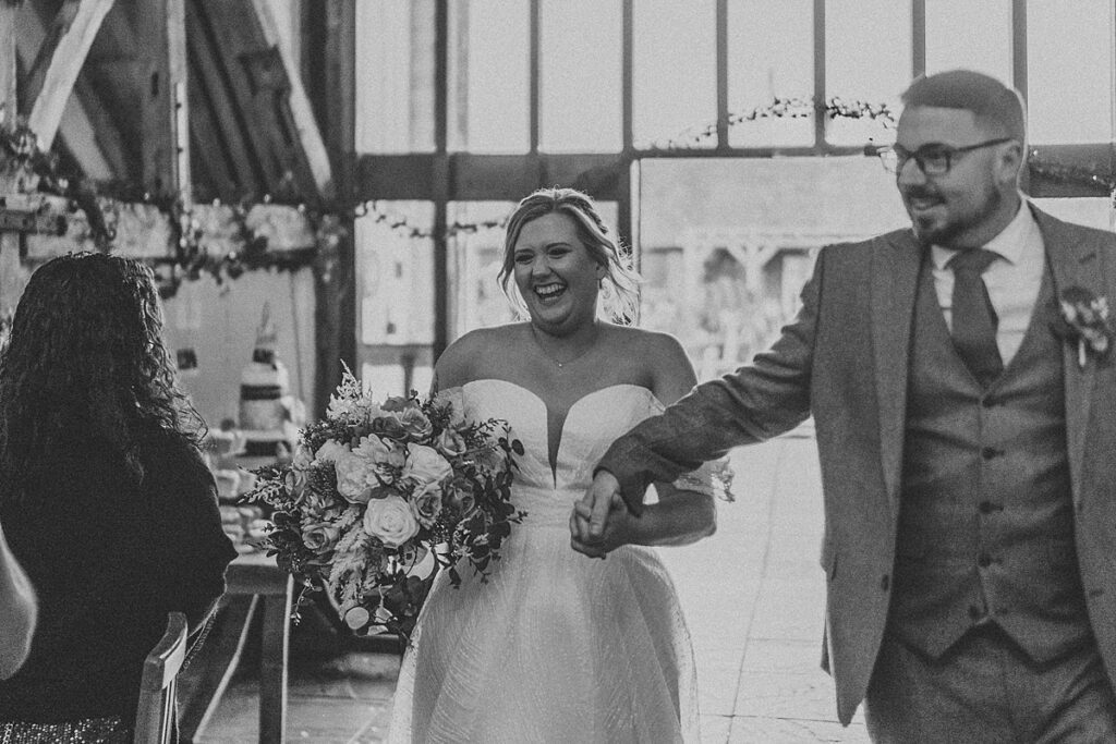 a bride and groom laughing as they walk into their wedding reception room