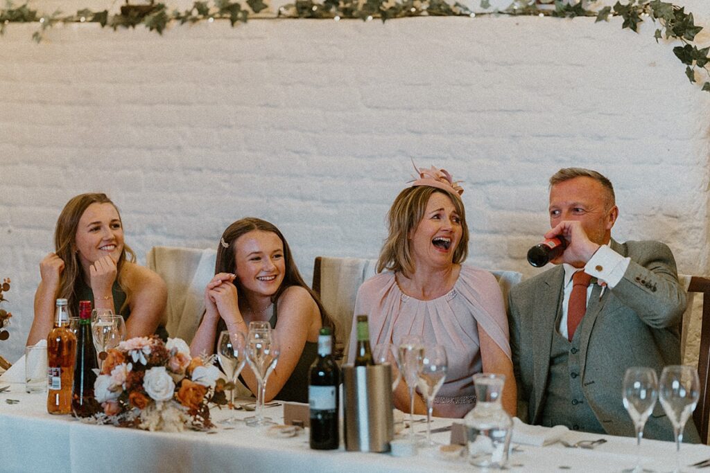 a wedding party laughing hysterically during the wedding speeches at Ufton Court