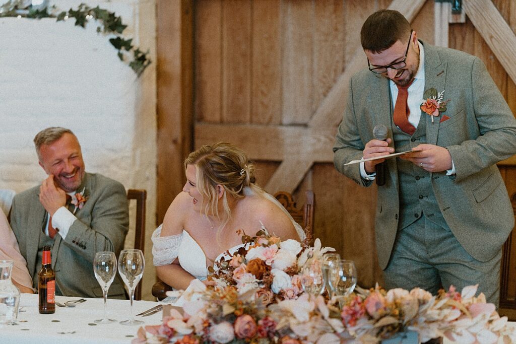 a bride laughing as her new husband gives his speech