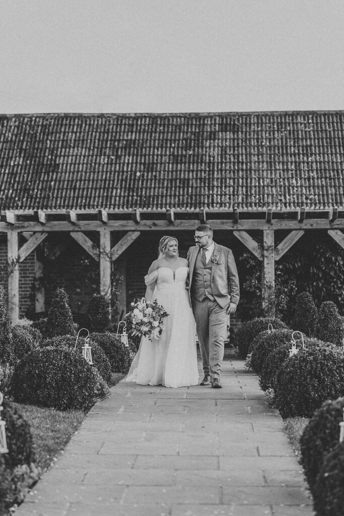 a newly wed couple chatting as they walk for a wedding photographer at Ufton Court