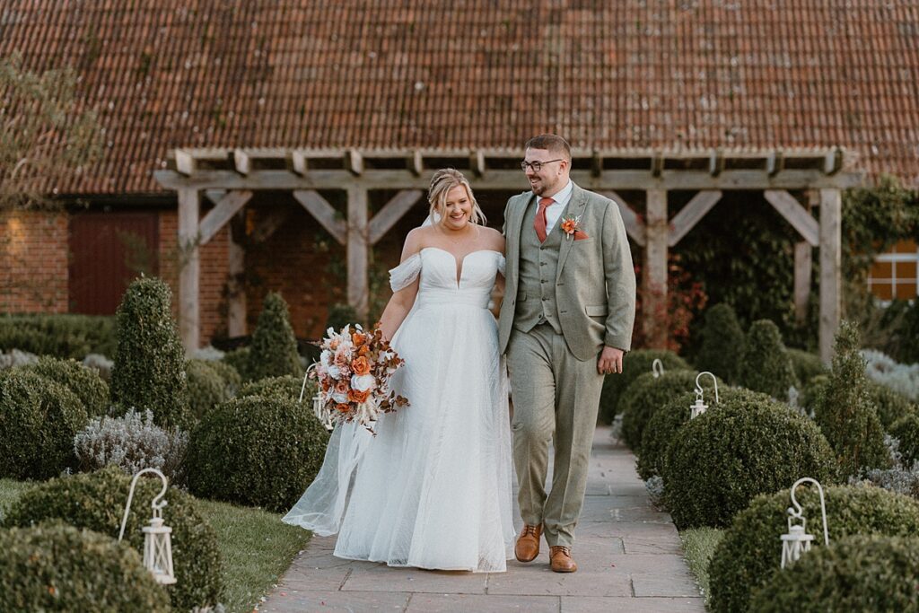 a newly wed couple chatting as they walk for a wedding photographer at Ufton Court