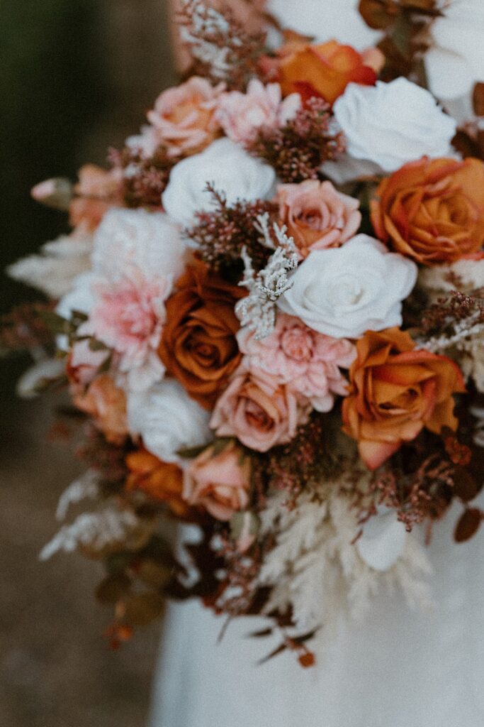 a close up of a brides white, pink and orange bouquet