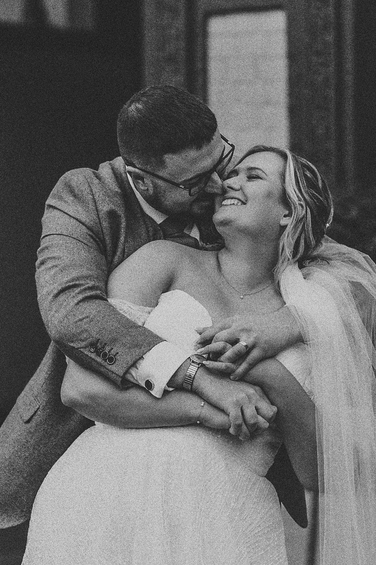 a groom hugging on to his new bride and laughing during their couple portraits at Ufton Court