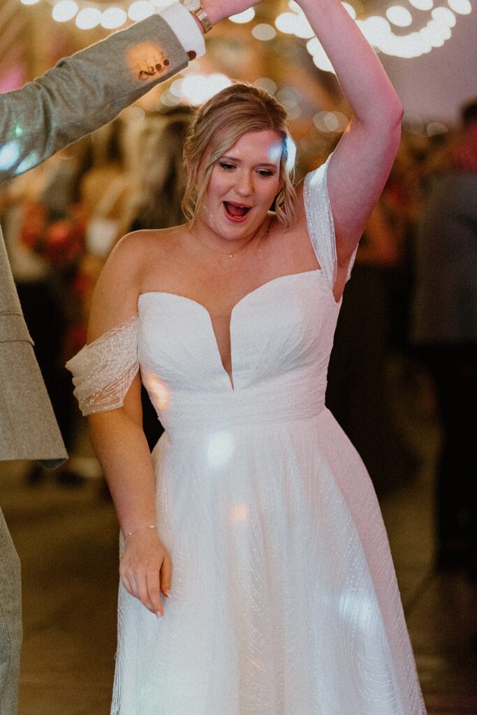 a bride cheering as she dances on the dance floor at Ufton Court Aldermaston