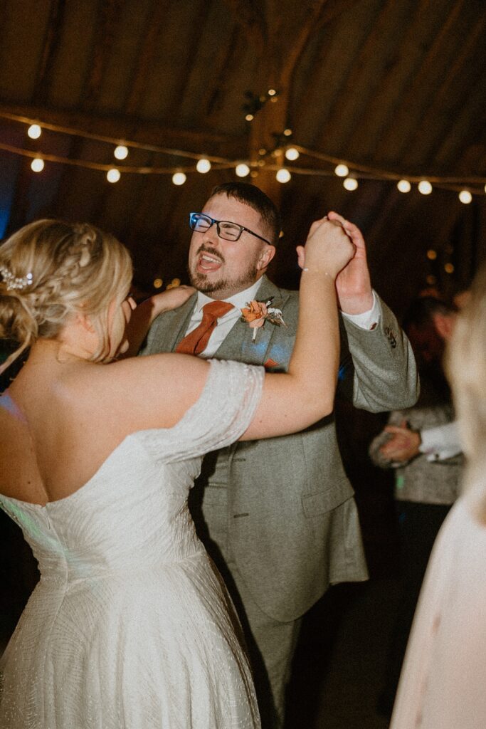 a bride and groom dancing together as the groom sings during their reception