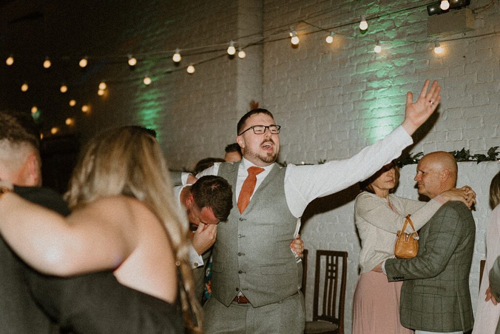 a groom sings loudly as he dances and hugs his bestman at Ufton Court