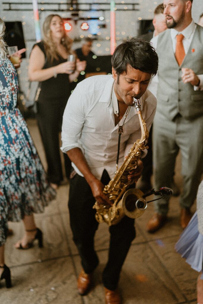 a saxophone player playing along to the djs music at a wedding party at Ufton Court