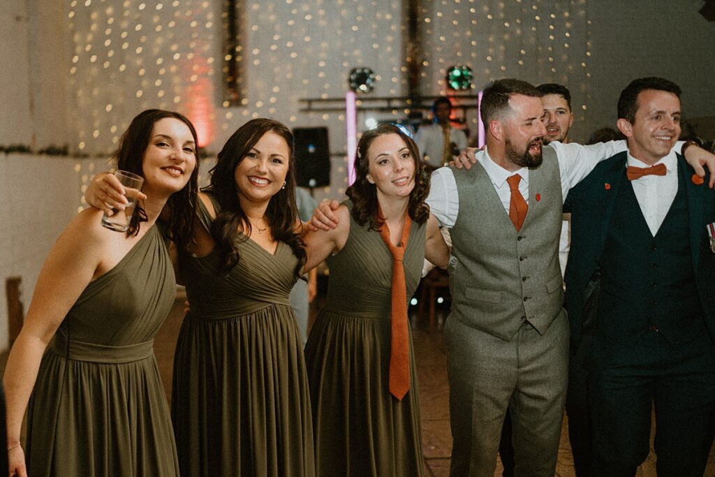 a few wedding party guests hugging on to each other and posing for a wedding photographer at Ufton Court