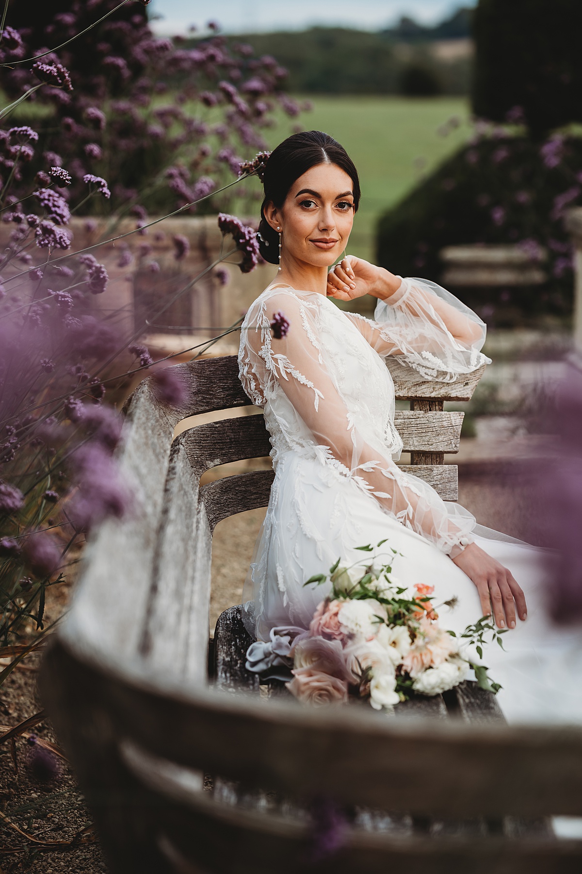 a bride sat on a stone seat surrounded by lavender during a bridal photoshoot taken by a luxury cotswolds wedding photographer