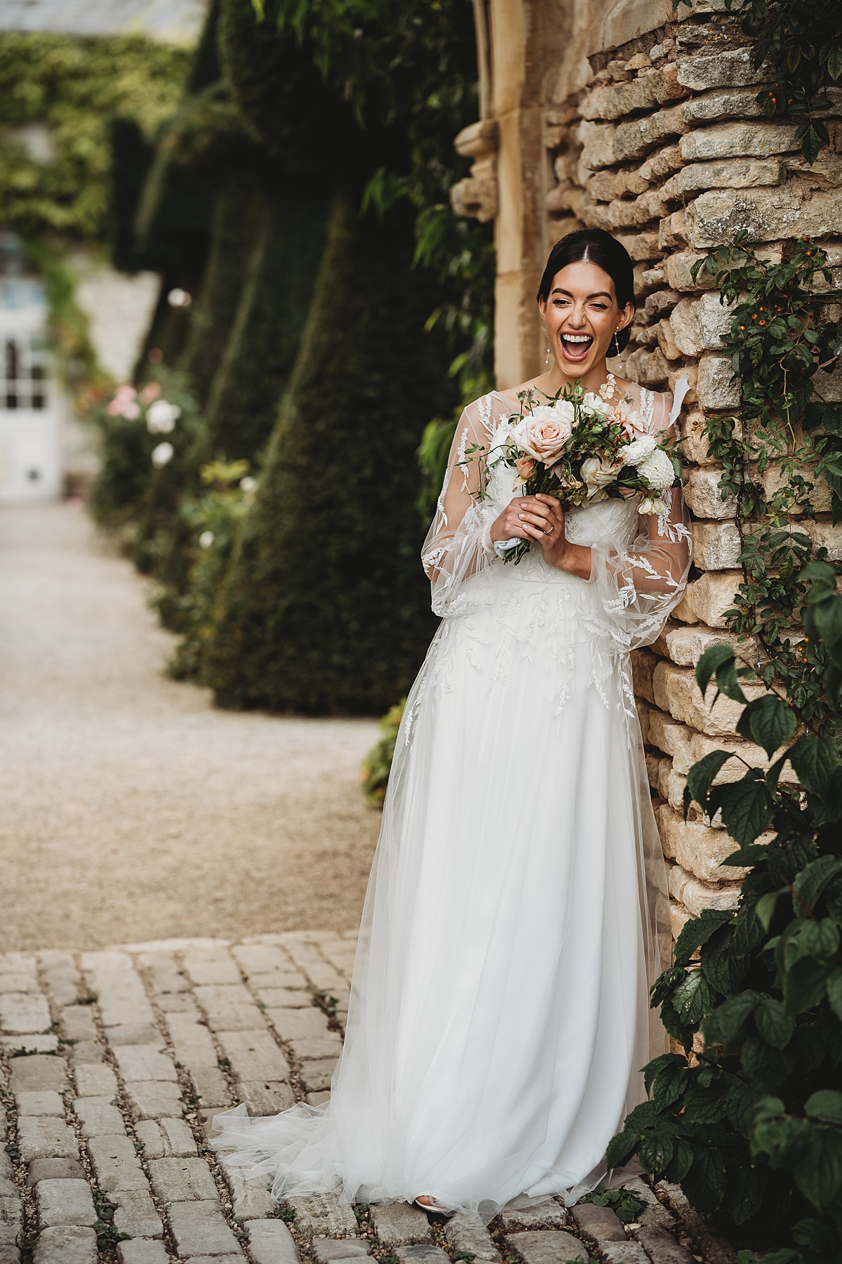 a bride laughing as she leans against a wall during her bridal portraits at Euridge Manor