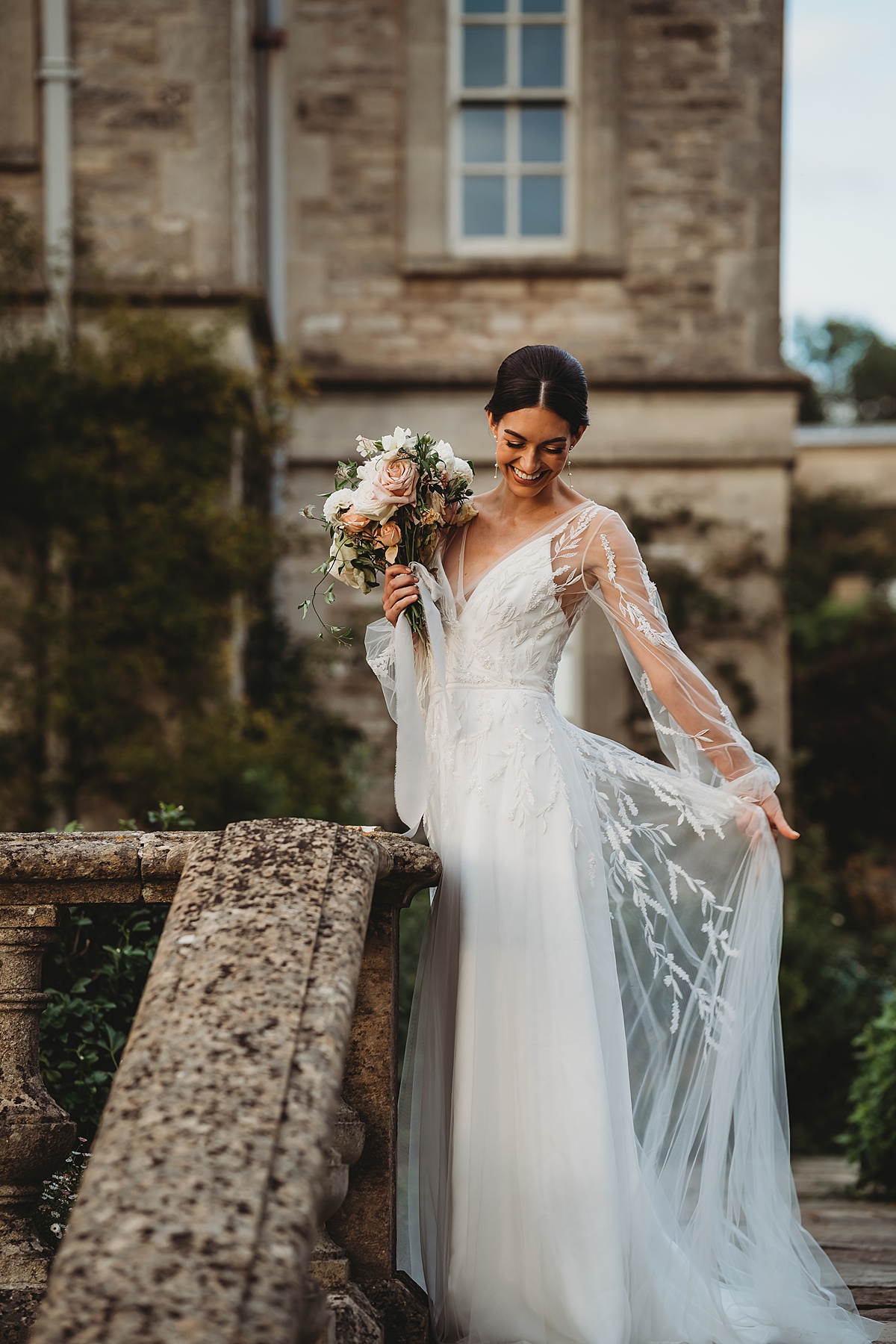 a bride playing with her flowing bridal dress during her sunset bridal portraits taken by a cotswolds wedding photographer