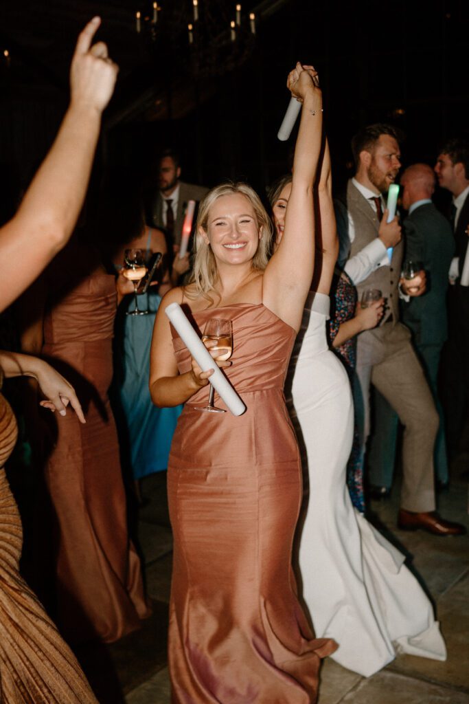 a bridesmaid smiling to the camera in the middle of a wedding dance floor