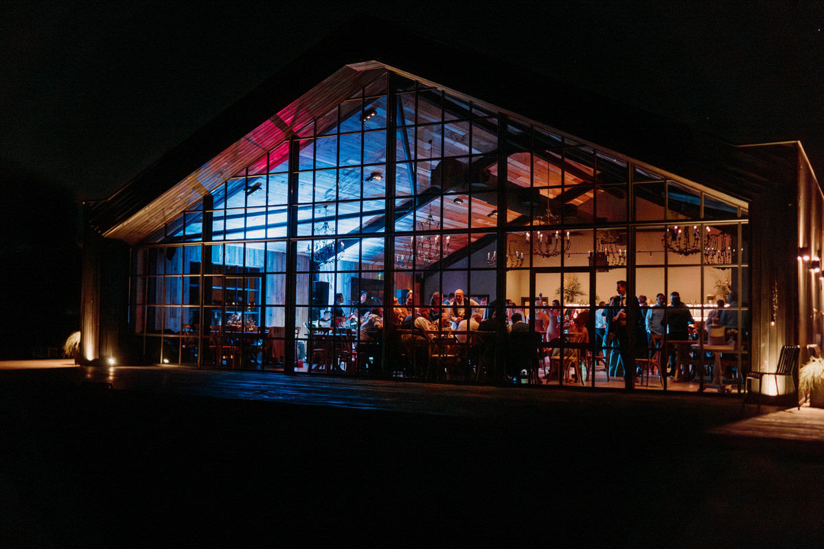 The inside of Botley Hill Barn taken from the outside as the wedding party is in full swing by a luxury wedding photographer