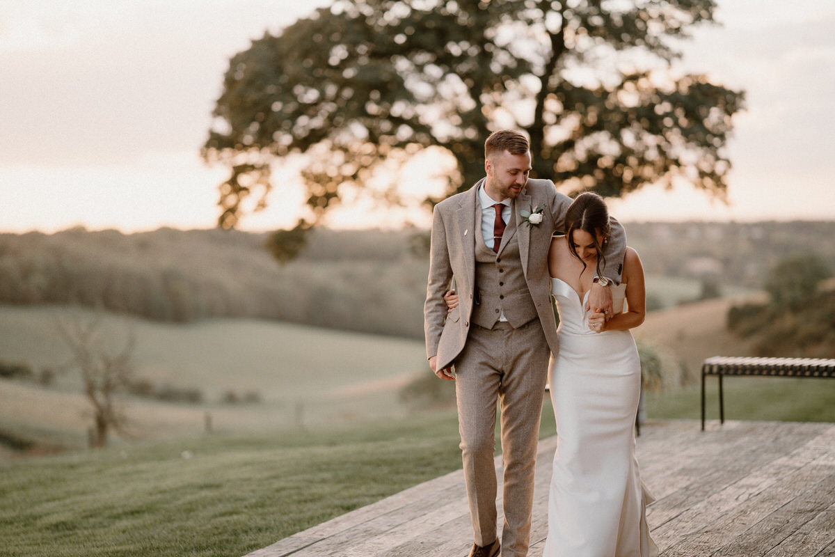 a groom hugs his new wife as they walk and chat together