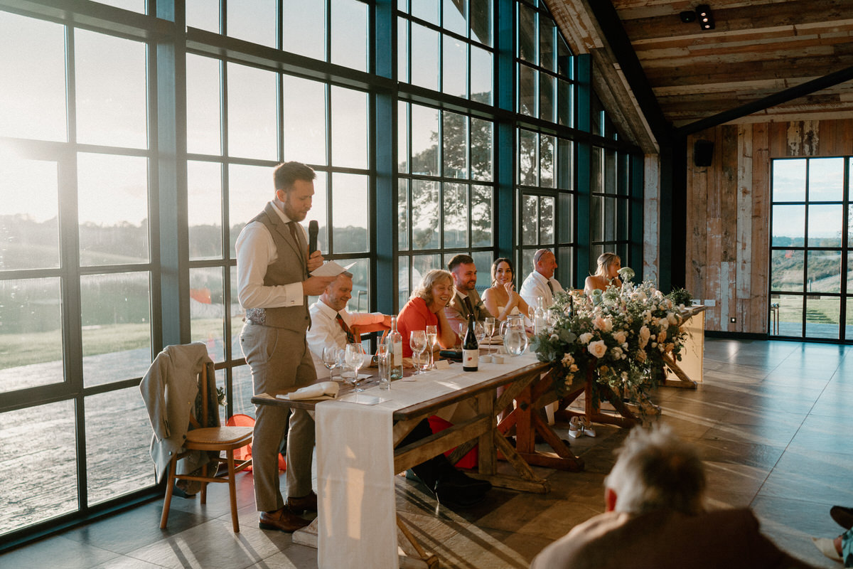 a bestman stands at the end of the head table as he gives his bestman speech