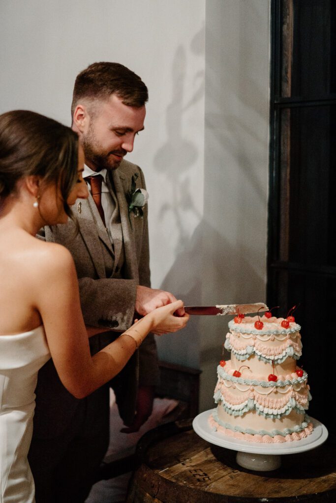 a bride and groom cutting their wedding cake for their luxury barn wedding