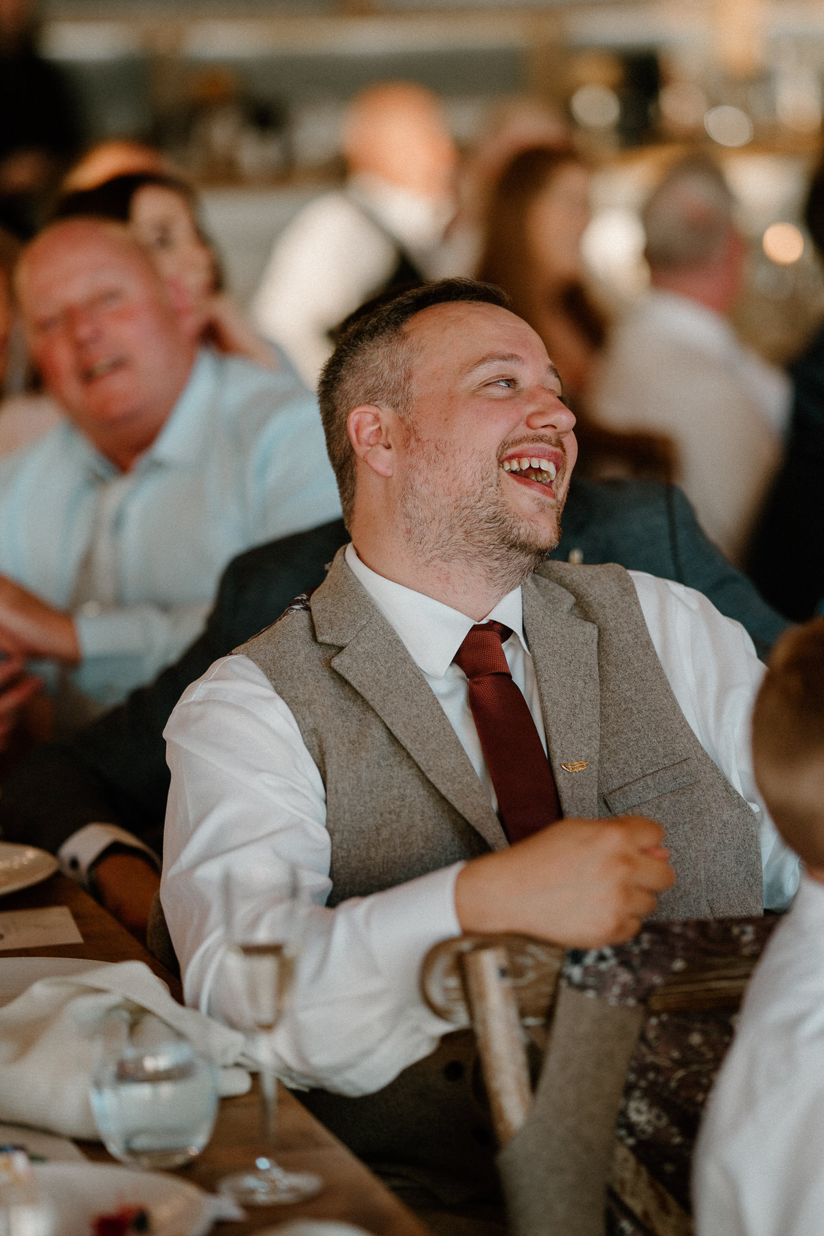 one of the groomsmen laughing as he listens to a bestman speech