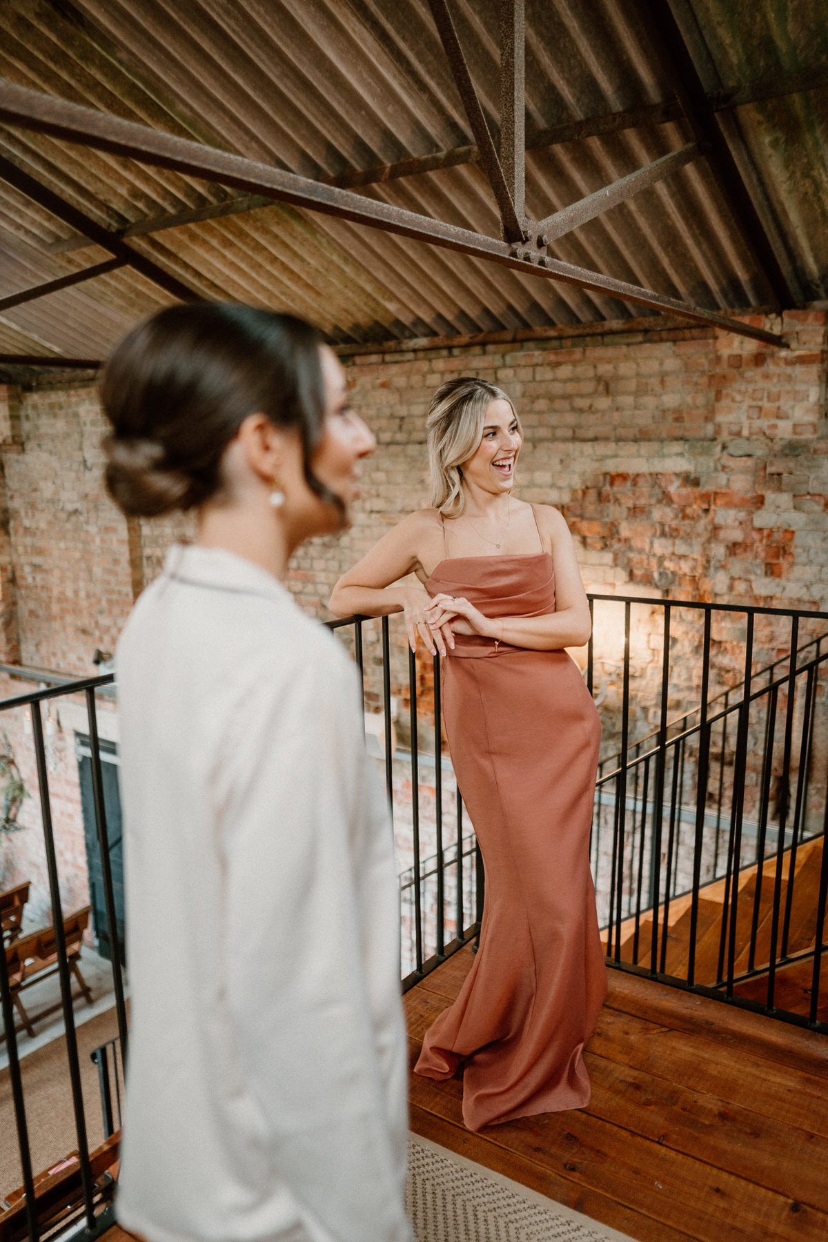 a bridesmaid casually leaning against railings as she chats to the bridal party