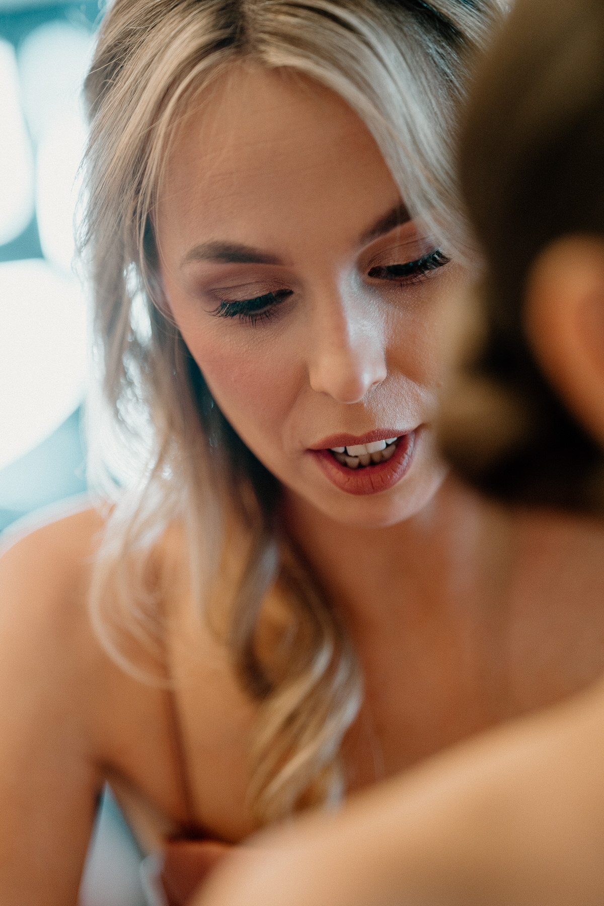 a bridesmaid concentrating as she does up her sisters bridal dress taken by Botley Hill Barn Luxury Wedding Photographer