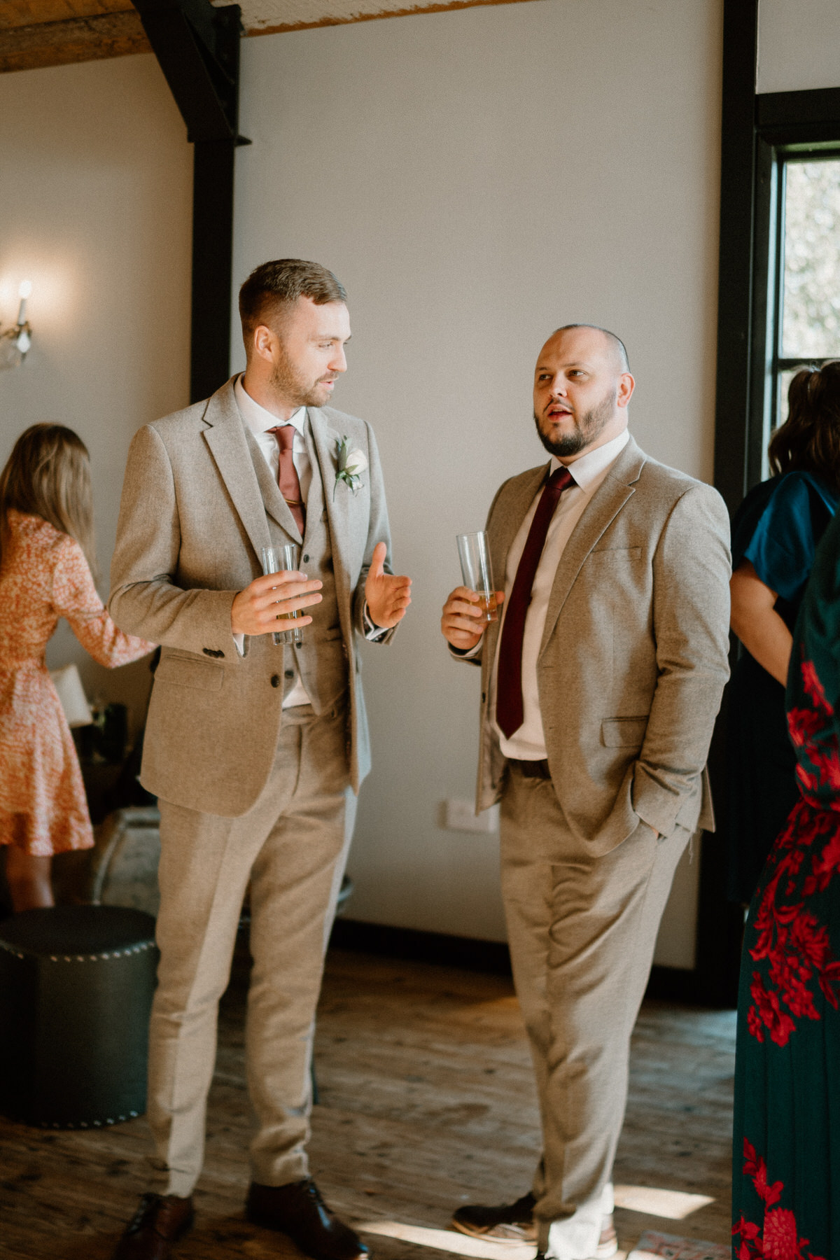 a groom chatting with a guest whilst having a pint during a wedding reception