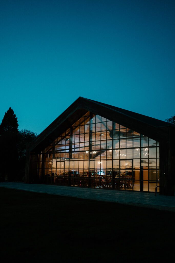 a luxury wedding barn at night showing the wedding reception happening through the window