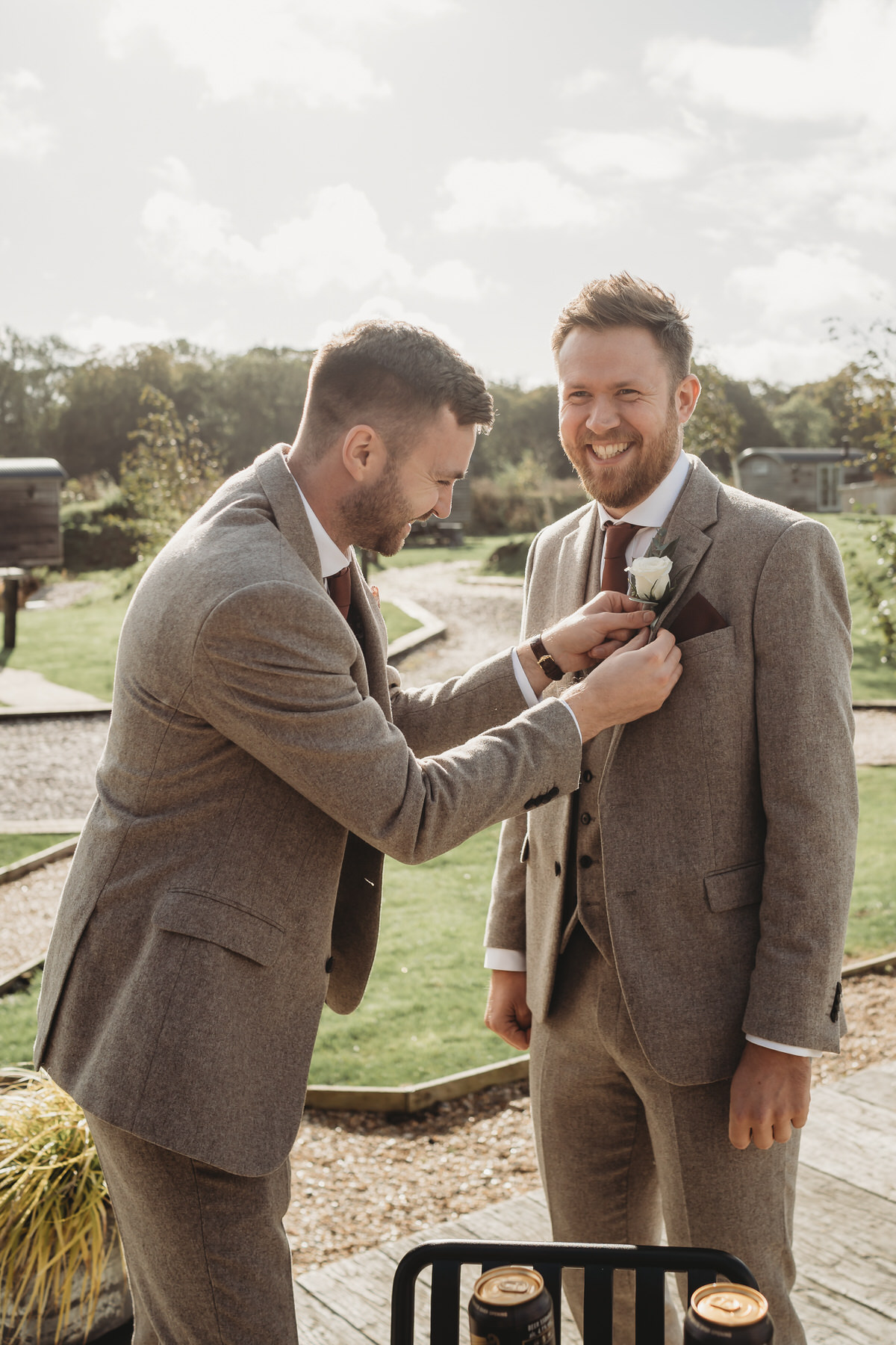 the groom helping a groomsman with his button hole before the wedding ceremony in Surrey