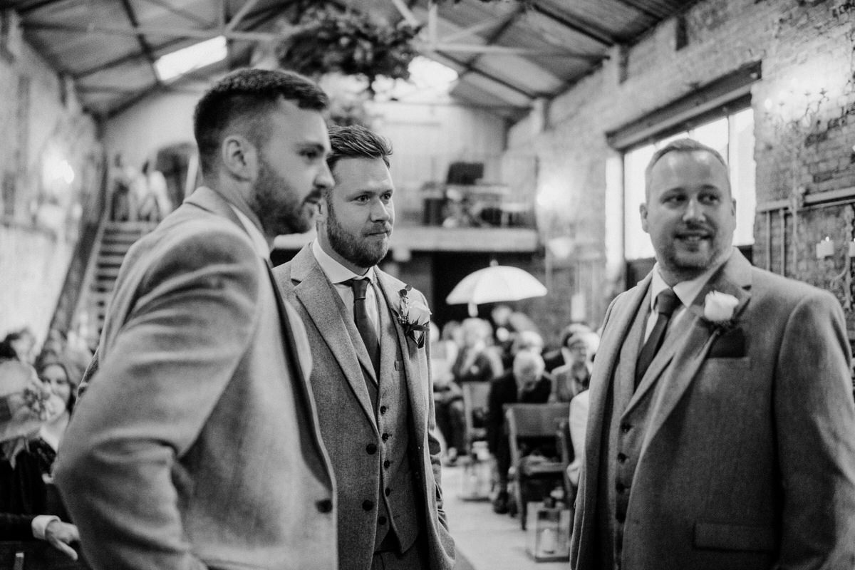 groom and groomsmen stood chatting at the front of the ceremony room waiting for the wedding to start at a luxury wedding venue