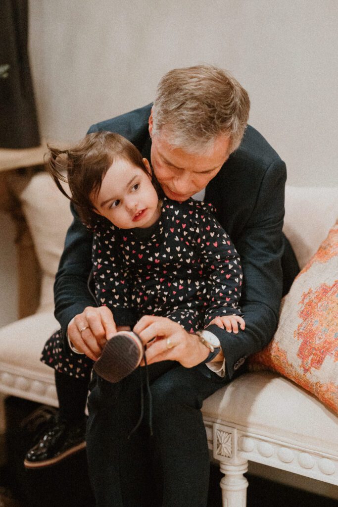 a grandad helping his granddaughter with her shoes at a wedding reception venue