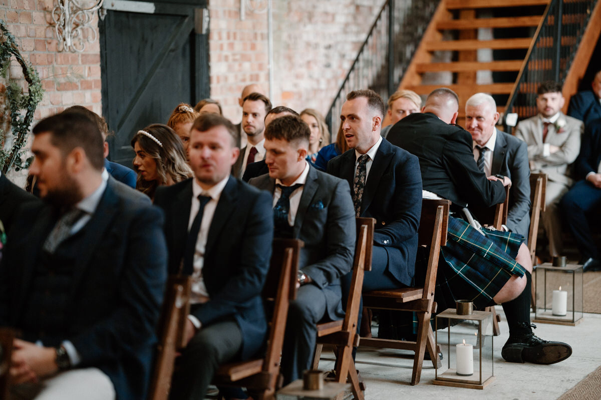 a row of male guests sat waiting for a wedding ceremony to start