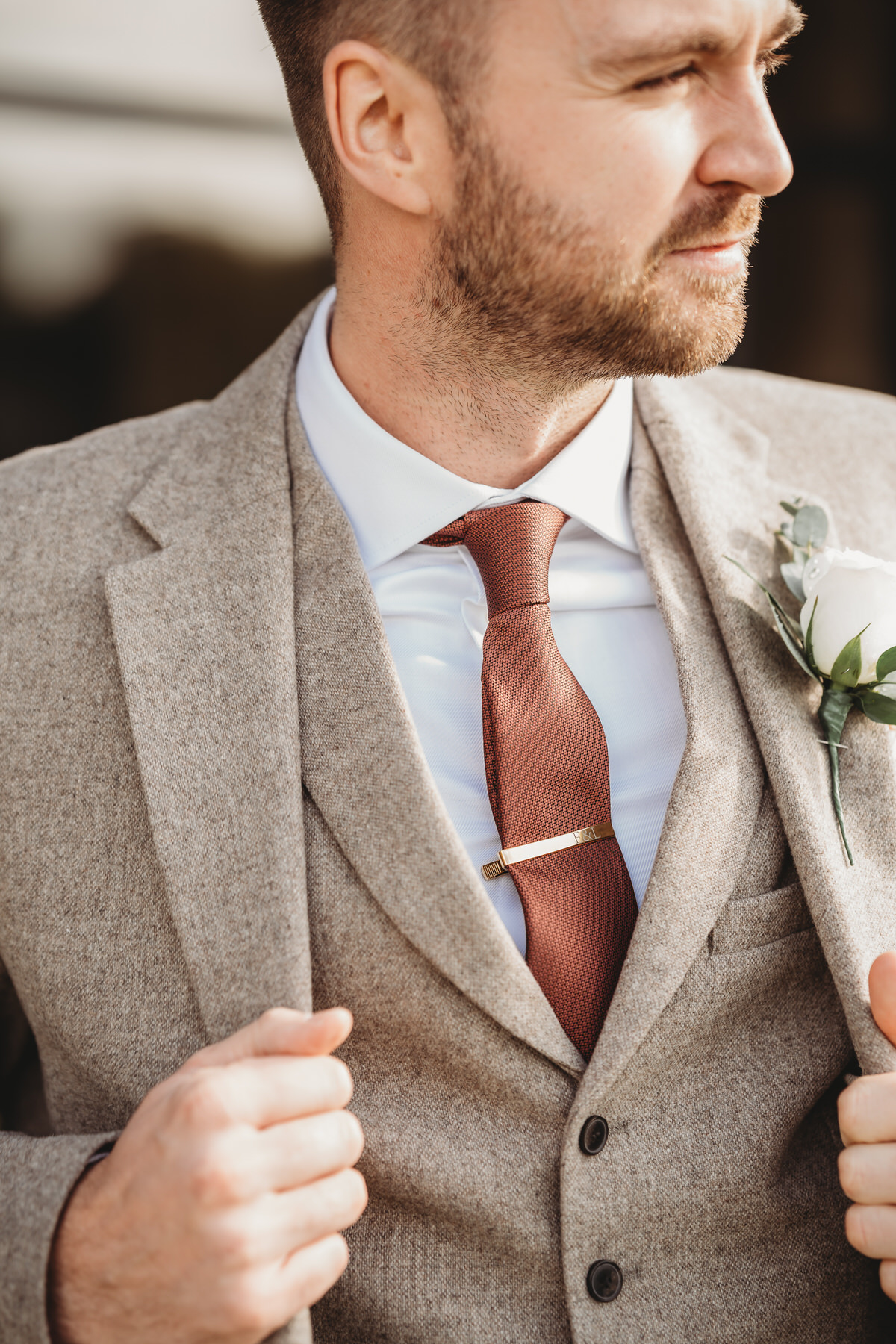 a close up of a groom adjusting the jacket to his three piece suit before his wedding at Botley Hill Barn