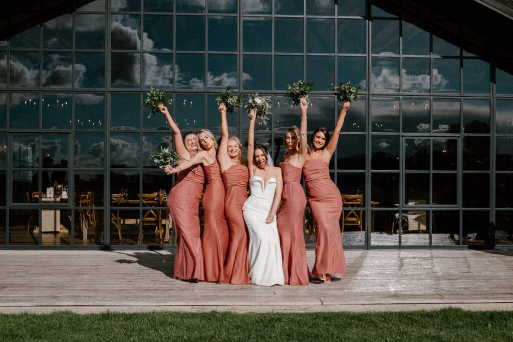 bridal party holding their hand up in the air in celebration after a barn wedding